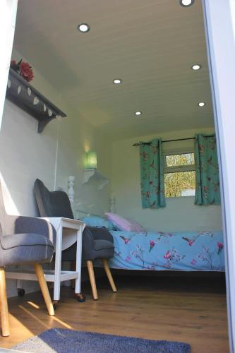 a bedroom with a bed and two chairs and a table at Hopgarden Glamping and camping - Luxury furnished Bell tents & Shepherd huts plus camp field to pitch your own tents in Wadhurst