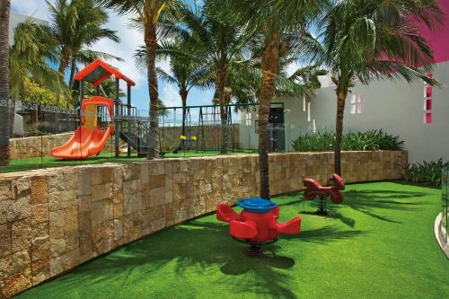a park with a playground with a slide and palm trees at Krystal Grand Cancun All Inclusive in Cancún