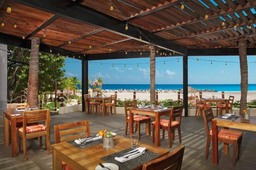 a restaurant on the beach with tables and chairs at Krystal Grand Cancun All Inclusive in Cancún