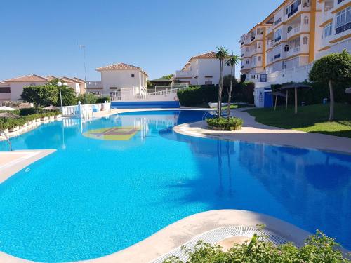 a large blue swimming pool with buildings in the background at Park Beach La Mata in La Mata