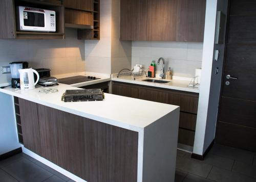 cocina con encimera y microondas en Kennedy Premium Apartments Colorado, en Santiago
