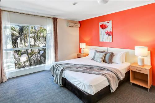 1 dormitorio con 1 cama grande y pared de color naranja en Coral Tree Inn en Cairns