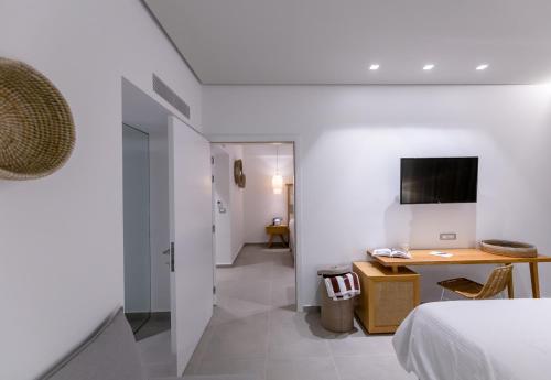 a bedroom with a bed and a desk and a television at Messinian Icon Hotel & Suites in Kalamata