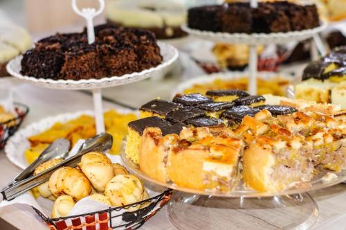 a table filled with different types of cakes and desserts at Pousada Nascer do Sol in Penha