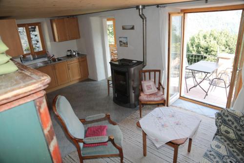 a kitchen with a stove and chairs and a balcony at Casa Flora in Verdabbio