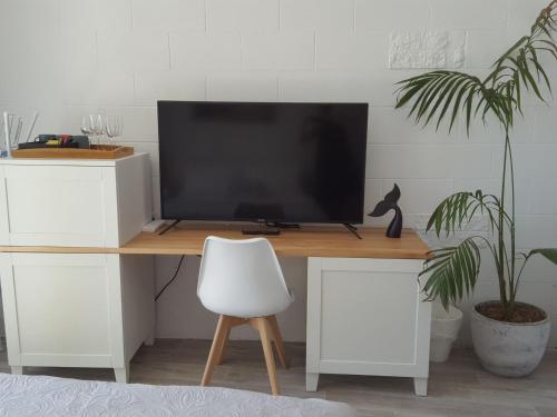 a desk with a television and a white chair at Peninsula Beach Motel in Rosebud