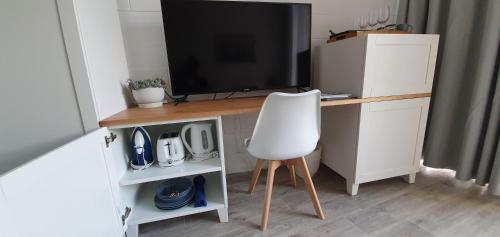 einen Schreibtisch mit einem TV und einem weißen Stuhl in der Unterkunft Peninsula Beach Motel in Rosebud