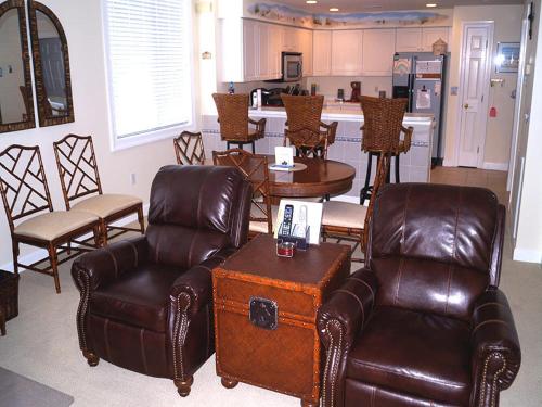 a living room with leather chairs and a kitchen at Ocean'S Edge 401 Condo in Ocean City