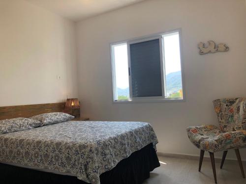 a bedroom with a bed and a chair and a window at Cobertura em Ubatuba in Ubatuba