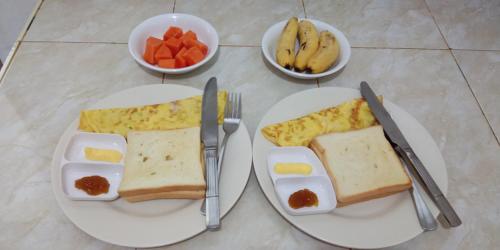 Dois pratos brancos com pequeno-almoço e tigelas de fruta em Rosalina Homestay em Rantepao