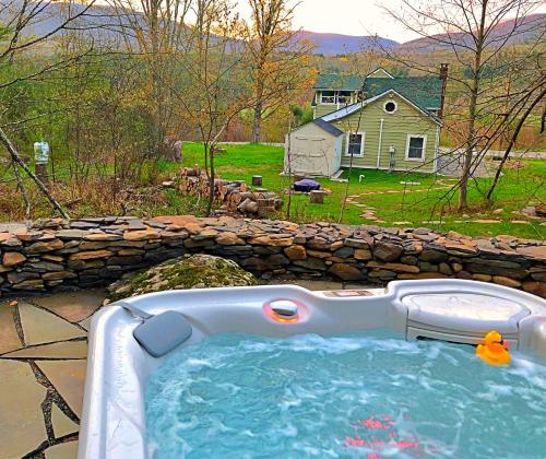a hot tub in a yard with a stone wall at Romantic, Magical Cottage in Catskills nr Woodstock in Willow