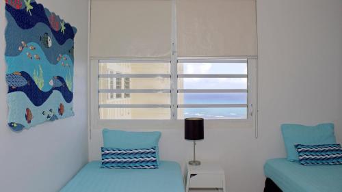 a bedroom with two blue chairs and a window at Montemar in Luquillo