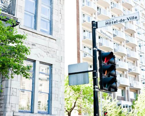 a traffic light with a street sign in front of a building at Auberge du Plateau in Montréal