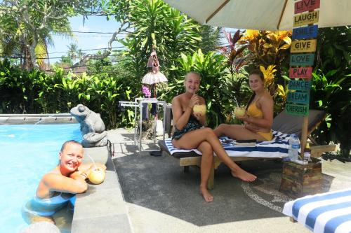 three girls in bathing suits sitting next to a swimming pool at SunwuKong Guest House in Ubud