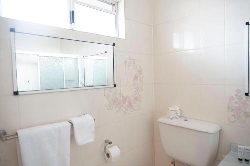 a white bathroom with a toilet and a window at Motel Nomad in Cairns