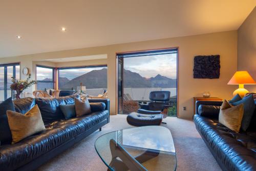 a living room with a leather couch and a glass table at London Lane in Queenstown