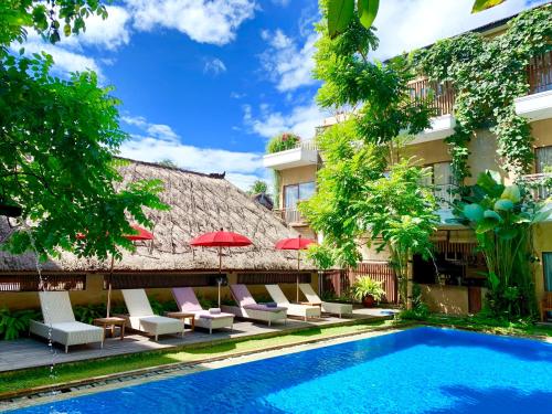a resort with a swimming pool and chairs and a building at Hotel Puriartha Ubud - CHSE Certified in Ubud
