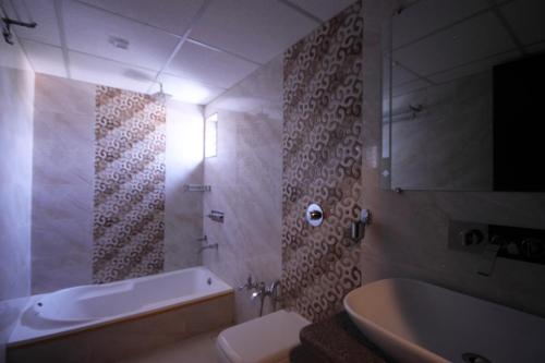 a bathroom with a tub and a toilet and a sink at Hotel Furaat Inn in Ahmedabad