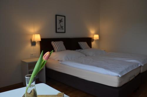 Un dormitorio con una cama y un jarrón con una flor en Weingut Erbes-Henn, en Ürzig