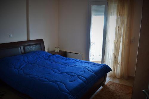 Un dormitorio con una cama azul y una ventana en Aegean View, en Platána