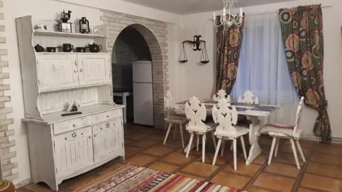 ボウコビヤにあるArkadia Dom nad Jeziorem Solińskimのキッチン(テーブル、白いキャビネット、椅子付)