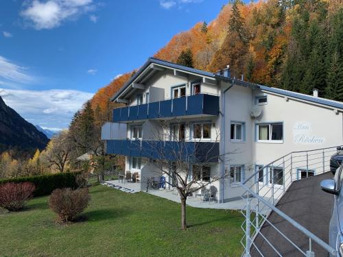 a white building with blue balconies on a hill at Haus Röcken in Dalaas
