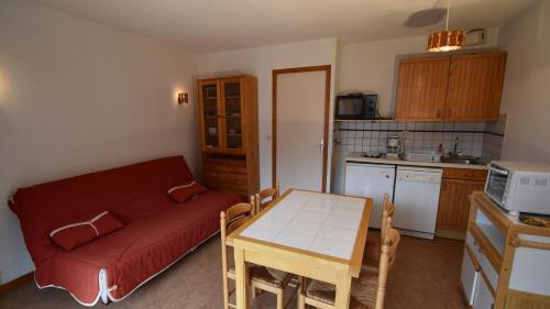 un salon avec un canapé rouge et une table dans l'établissement VAUJANYLOCATIONS - Claret II Studio 3, à Vaujany