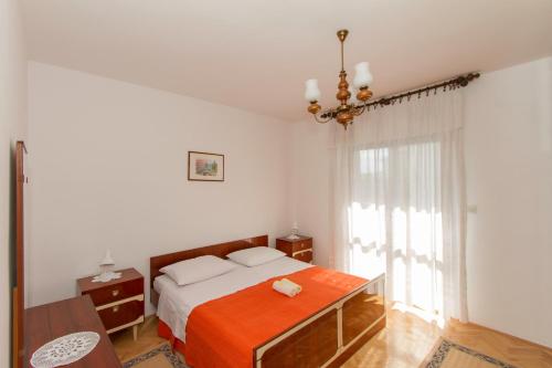 a bedroom with a bed with an orange blanket at Apartments Joso in Zadar