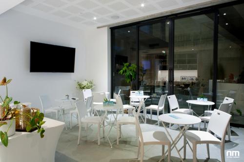 a restaurant with white tables and white chairs at Le B Complexe Hôtel in Lozanne