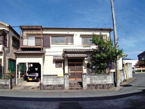 a white house with a car parked in front of it at ツバメハウス in Tenri