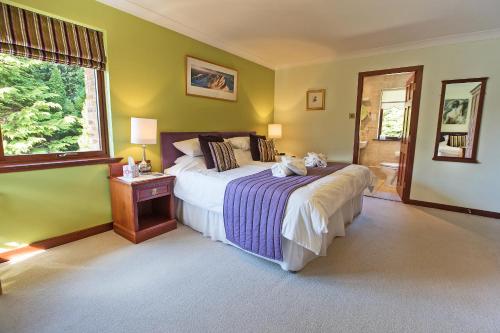 a bedroom with a large bed and a window at Glede Knowe Guest House in Innerleithen