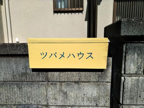una señal amarilla en el lateral de un edificio en ツバメハウス, en Tenri