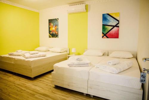 two beds in a room with yellow walls at Pansion Fočin Han in Sarajevo