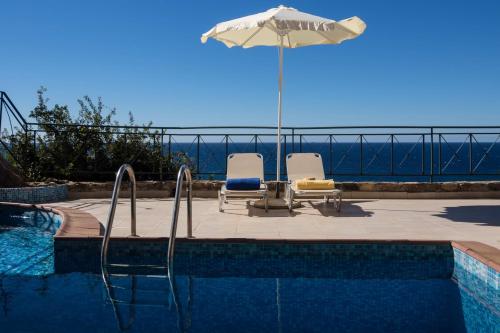 a swimming pool with two chairs and an umbrella at Meliti Sunset View & Private Pool Villa 20 min from Elafonissi in Livadia