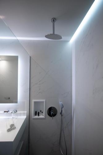 a white bathroom with a sink and a mirror at Messinian Icon Hotel & Suites in Kalamata