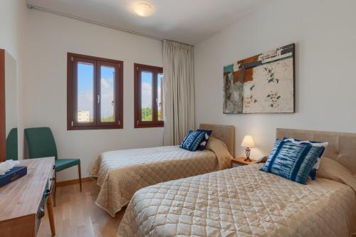 um quarto com 2 camas, uma secretária e janelas em Aphrodite Hills Rentals - Premium Serviced Apartments em Kouklia