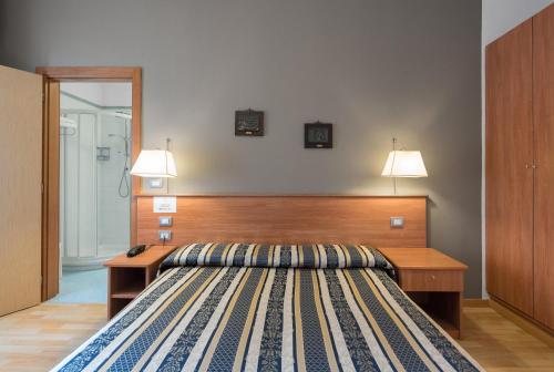 a bedroom with a bed and a desk with two lamps at Hotel Piccolo in Verona