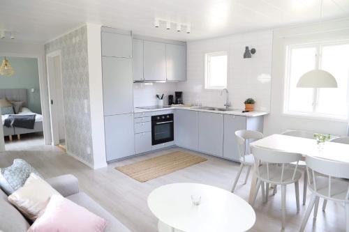 a kitchen and living room with white cabinets and a table at Tingsryd Resort in Tingsryd