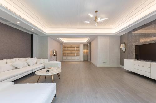 a living room with a white couch and a tv at HaitangBay Loosen Coast Resort Villas in Sanya