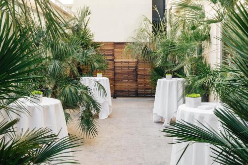 a row of tables with white table cloths and palm trees at Hotel Villa Real, a member of Preferred Hotels & Resorts in Madrid