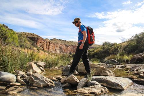 a man walking across rocks in a stream at Ganora Guest Farm, Camping and Excursions in Nieu-Bethesda
