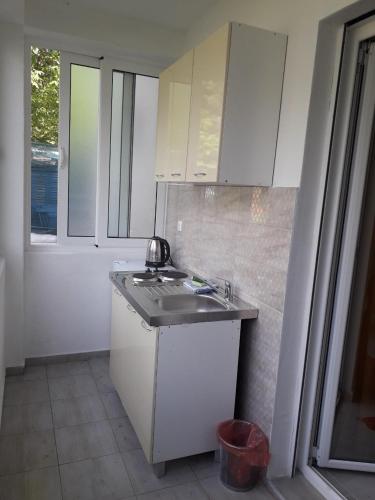a white kitchen with a sink and a window at Apartmani Andrea-jaz in Budva