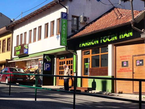 a man walking in front of a building on a street at Pansion Fočin Han in Sarajevo