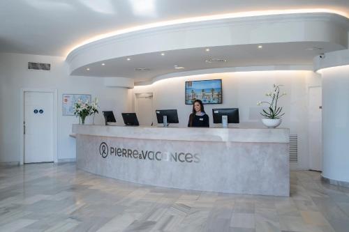 a woman standing at a counter in a lobby at Hotel El Puerto by Pierre Vacances in Fuengirola