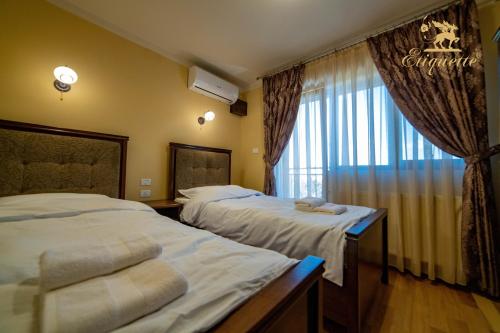two beds in a hotel room with a window at Villa Etiquette in Deva