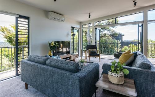 a living room with two couches and a table at Villas Waiheke in Onetangi