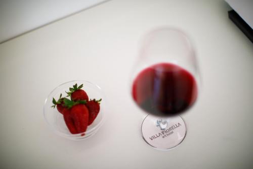 a glass of red wine and a bowl of strawberries at Villa Fiorella Art Hotel in Massa Lubrense