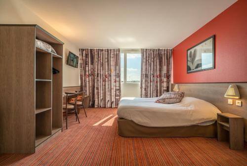 カーンにあるAce Hôtel Caen Nord Mémorialのベッドとデスクが備わるホテルルームです。