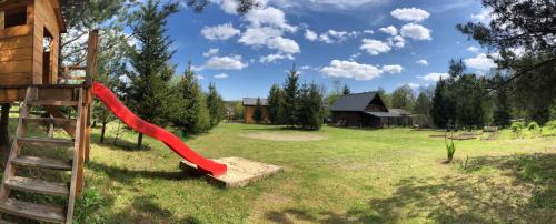 a playground with a red slide in a yard at Na Skraju Lasu in Guciów