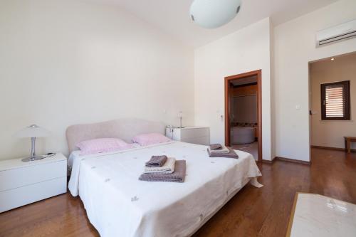 a white bedroom with a large bed with pink pillows at Astra Villas in Zaton